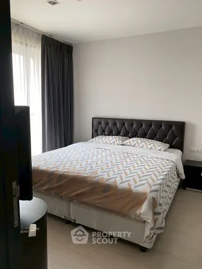 Spacious bedroom with modern decor and large window for natural light.