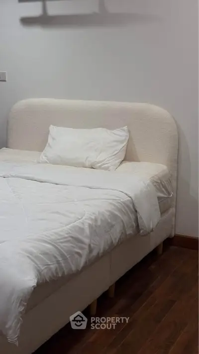 Cozy bedroom with plush bed and wooden flooring, perfect for restful nights.