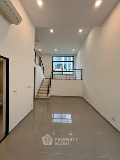 Spacious modern living room with high ceiling and staircase in a contemporary home