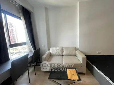 Modern studio apartment with cozy sofa, desk, and large window view.