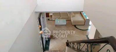 Spacious living room with elegant staircase and modern furniture, perfect for family gatherings.