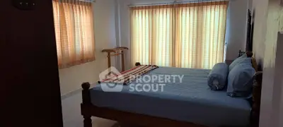 Cozy bedroom with wooden bed and natural light through large windows