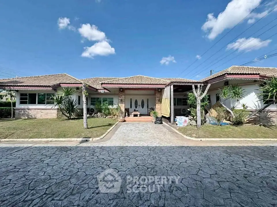 Charming single-story home with tiled roof and landscaped front yard under a clear blue sky.