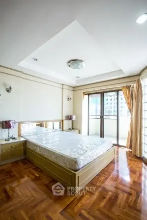 Spacious bedroom with large windows and balcony access in modern apartment.