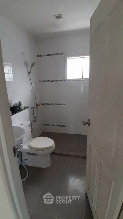 Modern bathroom with sleek design and shower area, featuring neutral tiles and natural light.
