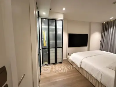Modern bedroom with sleek design, featuring a large bed, wooden flooring, and a wall-mounted TV for ultimate comfort.