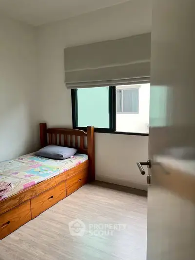 Cozy bedroom with wooden bed frame and large window for natural light.