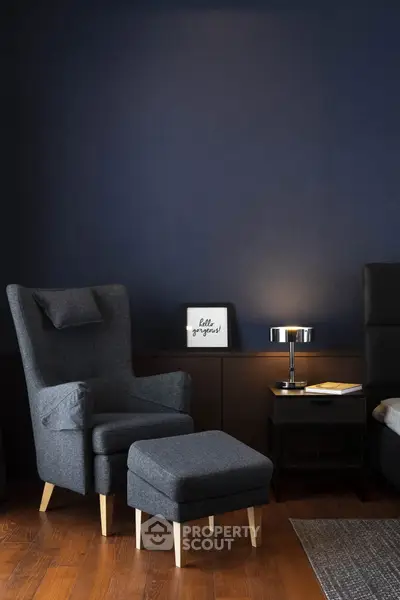 Stylish modern living room with dark blue walls, elegant armchair, and cozy lighting.