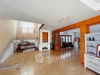 Spacious open-plan living area with wooden flooring and staircase