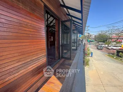 Charming wooden exterior with open windows and street view, perfect for a cozy home or business.