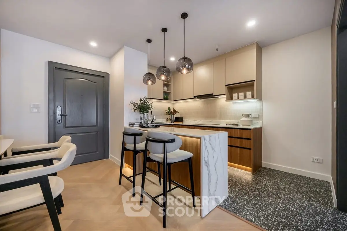 Modern kitchen with island, pendant lights, and sleek cabinetry in a stylish apartment.