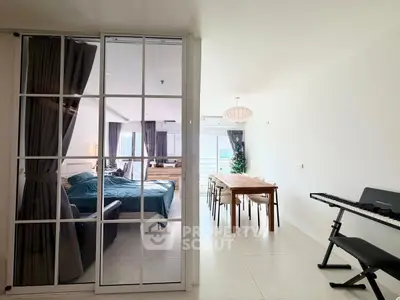 Modern open-plan living and dining area with glass partition and sleek furnishings.