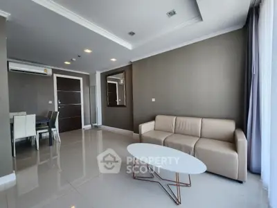 Modern living room with sleek furniture and dining area, featuring neutral tones and ample natural light.