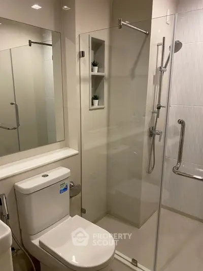 Modern bathroom with glass shower and sleek fixtures in contemporary apartment.