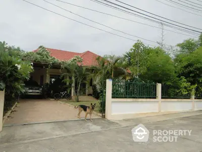 Charming suburban house with red roof, lush garden, and driveway in tranquil neighborhood.