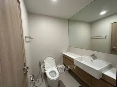 Modern bathroom with sleek fixtures and large mirror in contemporary home.