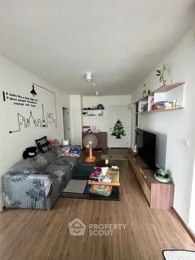 Modern living room with stylish decor and wooden flooring, featuring a cozy sofa and entertainment center.