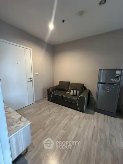 Modern living room with sleek sofa and refrigerator, perfect for urban living.