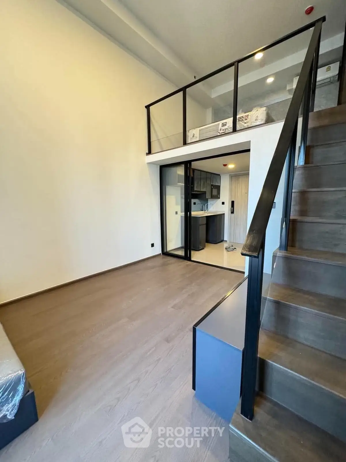 Modern loft apartment with mezzanine and sleek staircase, featuring open kitchen layout and high ceilings.