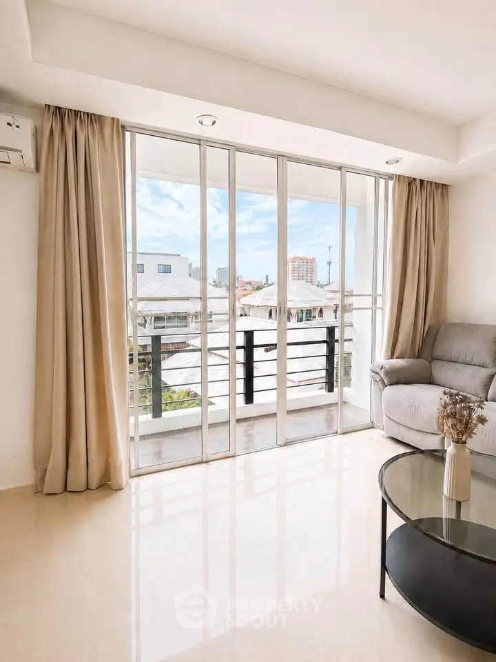Bright living room with large windows and balcony view, featuring modern furniture and elegant curtains.
