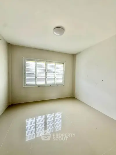 Spacious empty room with large window and glossy tiled floor, perfect for customization.