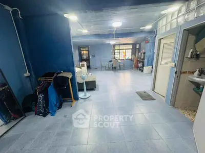 Spacious open-plan living area with blue walls and tiled flooring, featuring a cozy seating arrangement.