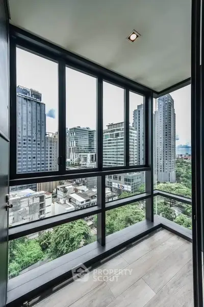 Stunning city view from modern high-rise balcony with floor-to-ceiling windows.