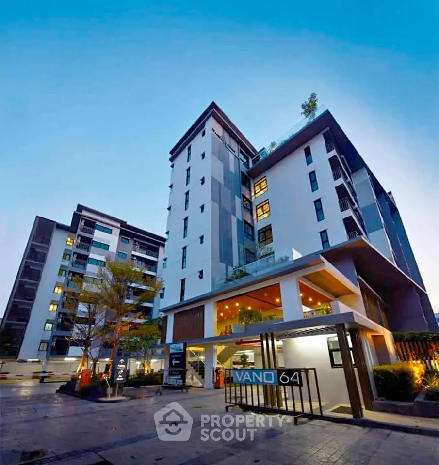Modern high-rise building with sleek design and illuminated entrance at dusk, showcasing urban living.