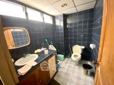 Spacious bathroom with blue tiles and modern fixtures in a well-lit setting.