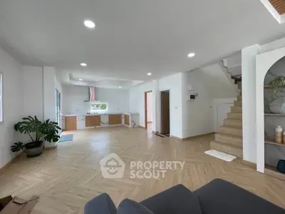 Spacious open-plan living room with modern kitchen and elegant staircase