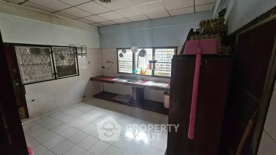 Spacious kitchen with tiled flooring and large windows for natural light.