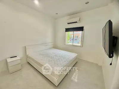 Spacious minimalist bedroom with white decor and large window view