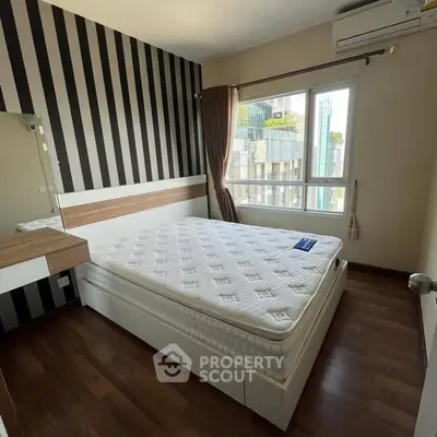 Modern bedroom with striped accent wall and large window offering city view