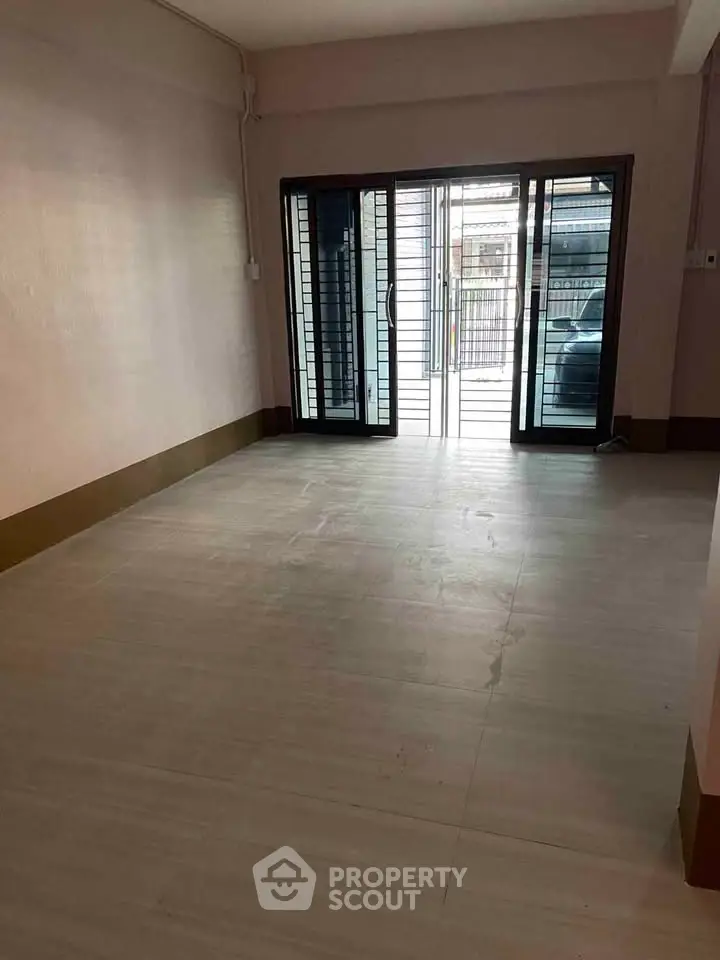 Spacious empty room with large sliding glass doors and tiled flooring