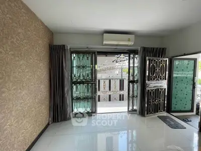Spacious living room with elegant wallpaper and large windows opening to a balcony.
