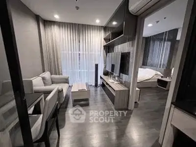 Modern living room with sleek furniture and open layout, adjacent to a cozy bedroom.