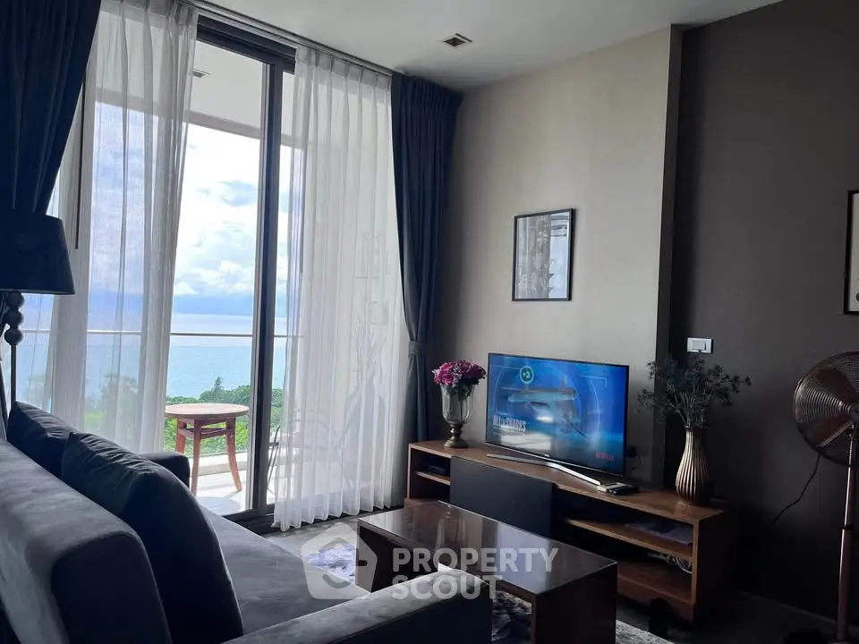 Modern living room with ocean view, featuring sleek furniture and floor-to-ceiling windows.