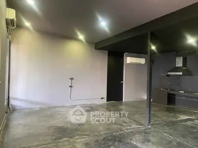Modern industrial-style room with concrete floors and minimalist kitchen.