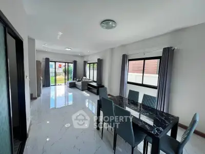 Spacious modern living and dining area with elegant marble table and large windows.