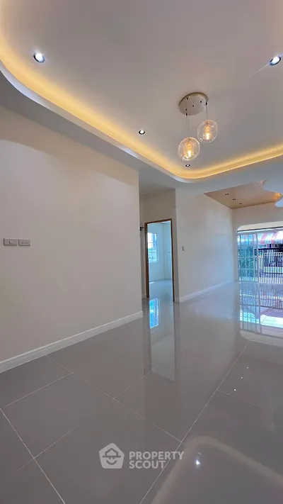 Spacious modern living room with glossy tiled floors and elegant ceiling lights.