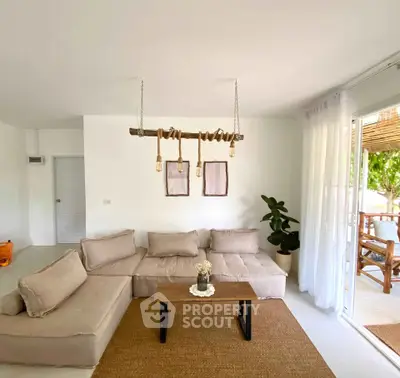 Chic living room with modern beige sofa, rustic decor, and natural light from large windows.