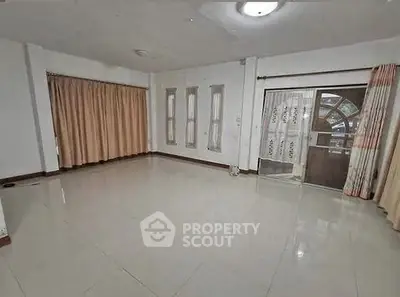 Spacious empty living room with large windows and tiled floor