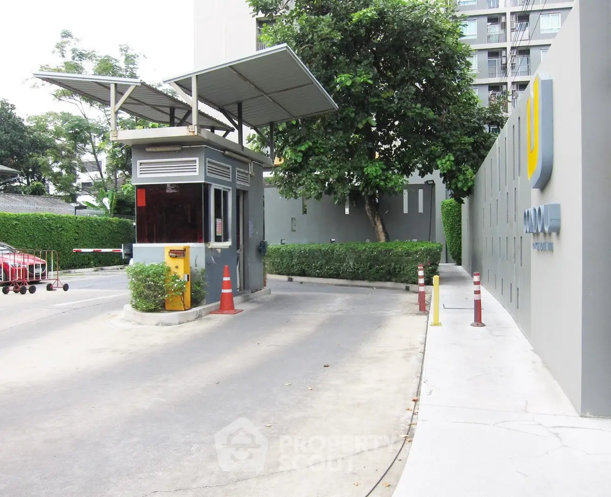 Modern building entrance with security booth and lush greenery