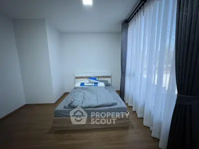 Modern minimalist bedroom with large window and wooden flooring