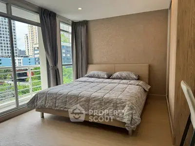 Modern bedroom with large windows and city view, featuring stylish decor and cozy ambiance.