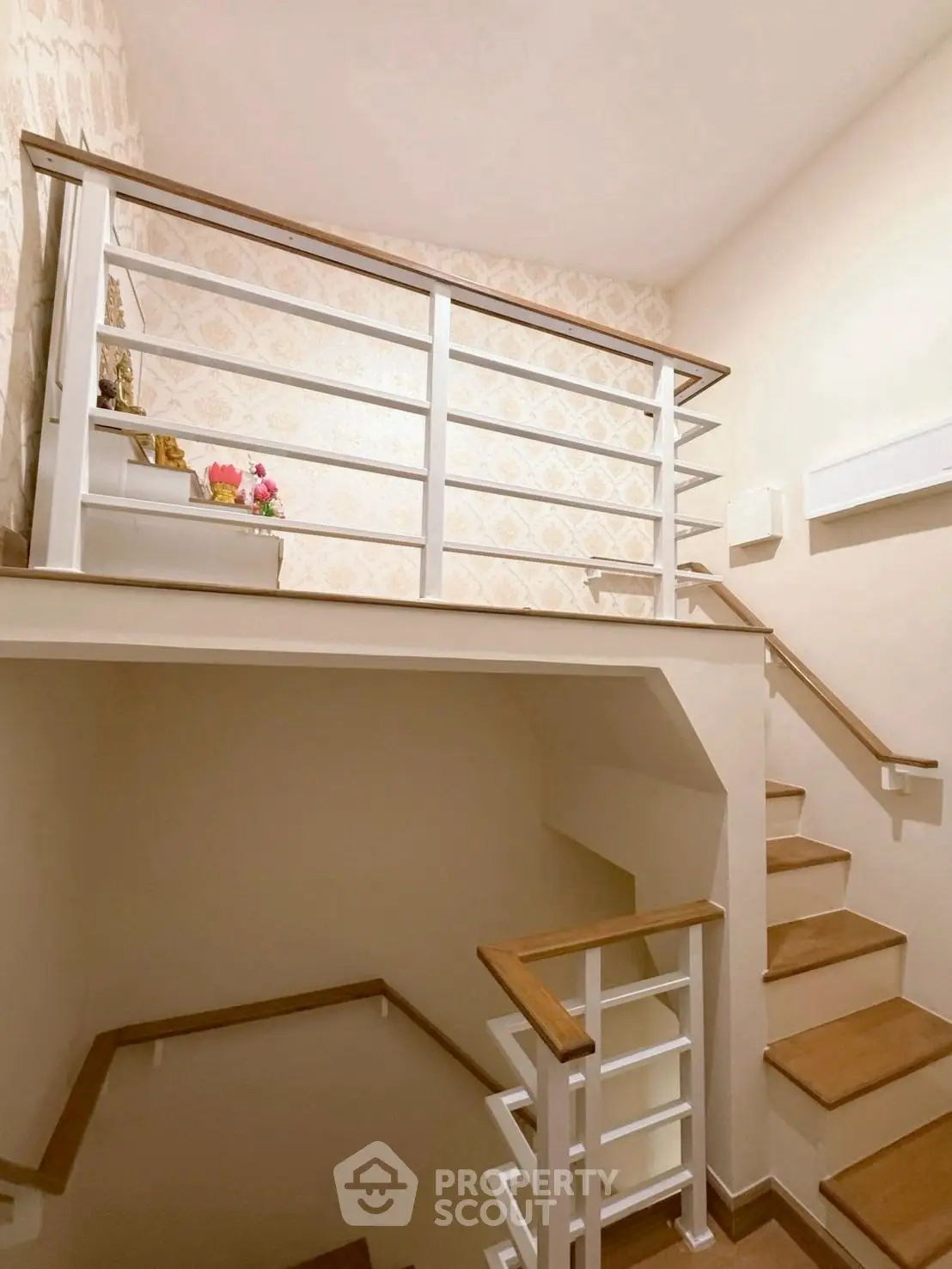 Elegant staircase with wooden handrails and decorative wallpaper in a modern home interior.