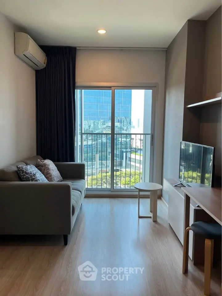 Modern living room with balcony view in a high-rise apartment, featuring sleek furniture and natural light.