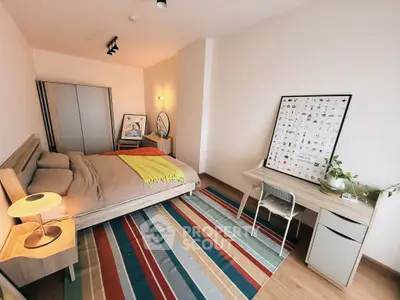 Modern bedroom with stylish decor, colorful rug, and cozy ambiance.