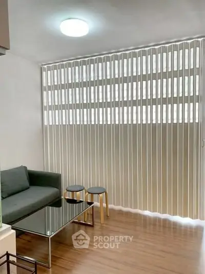 Modern living room with sleek furniture and vertical blinds, perfect for urban living.