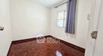 Spacious empty bedroom with wooden flooring and natural light.